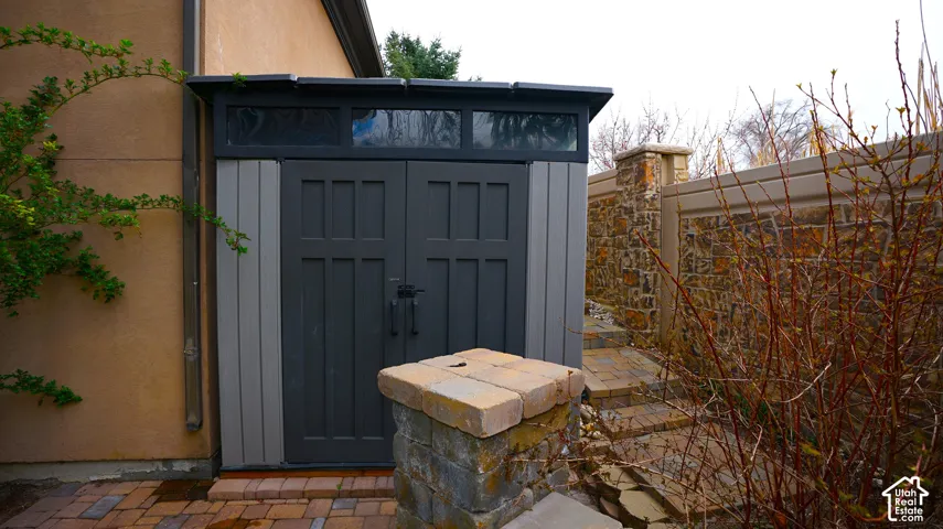 Custom storage shed with transom windows, stone accents, and paved path