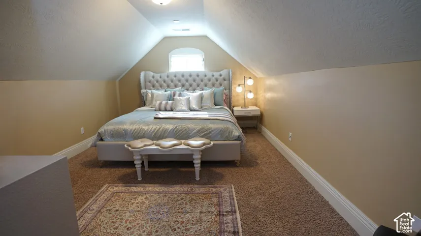 Vaulted ceiling, arched window, wall-to-wall carpeting, and white baseboards