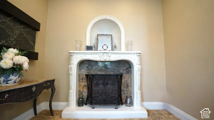 Ornate white fireplace surround with a dark stone-finish firebox, complemented by an arched niche