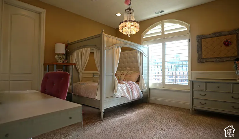 Arched window with plantation shutters, wainscoting, and a crystal chandelier