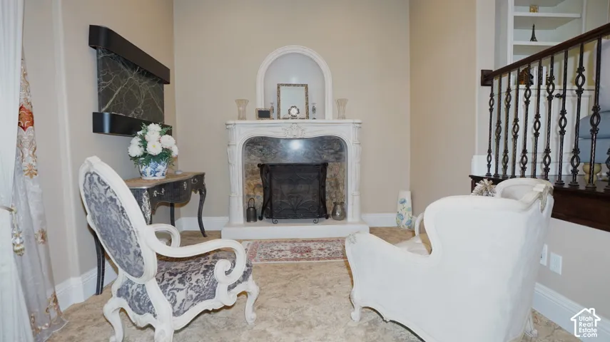 Ornate fireplace with a decorative mantel and hearth, built-in wall niche, wrought iron staircase railing, and built-in shelving