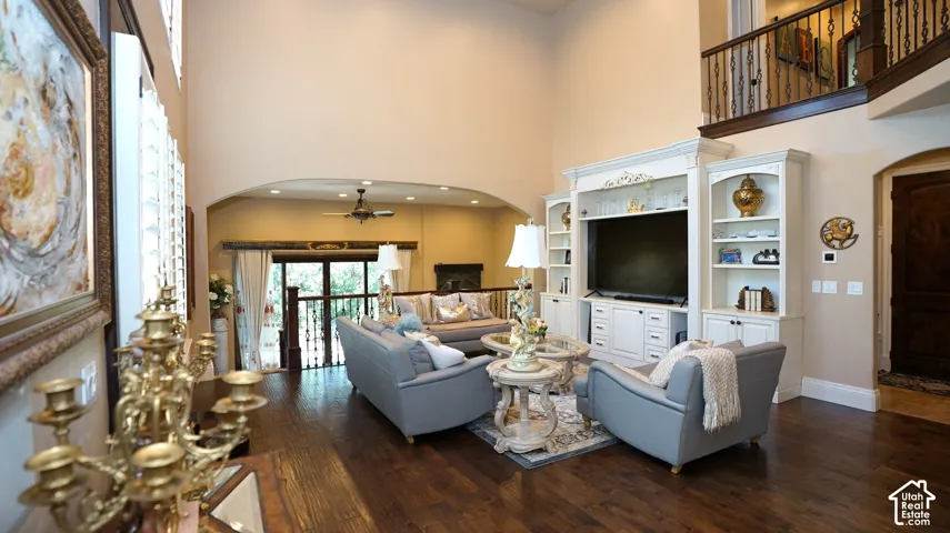 Expansive living area featuring soaring ceilings, dark wood-finish flooring, and a built-in entertainment center with integrated shelving