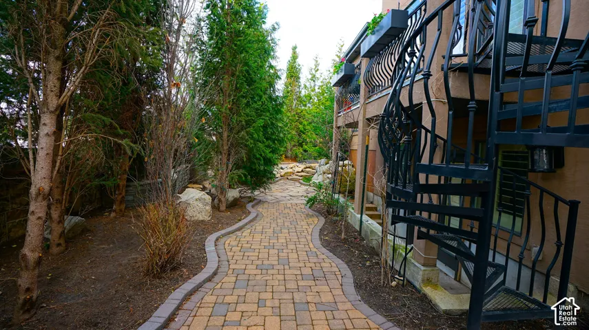 Paved walkway with stone edging, mature trees, and natural rock landscaping