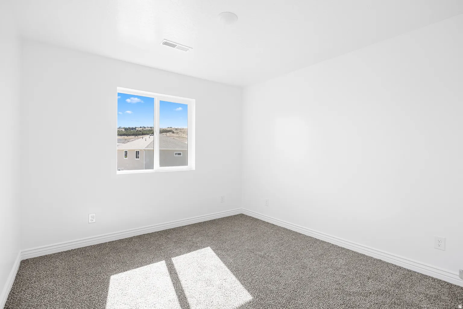 Crisp white walls, neutral carpet flooring, and a large window providing natural illumination