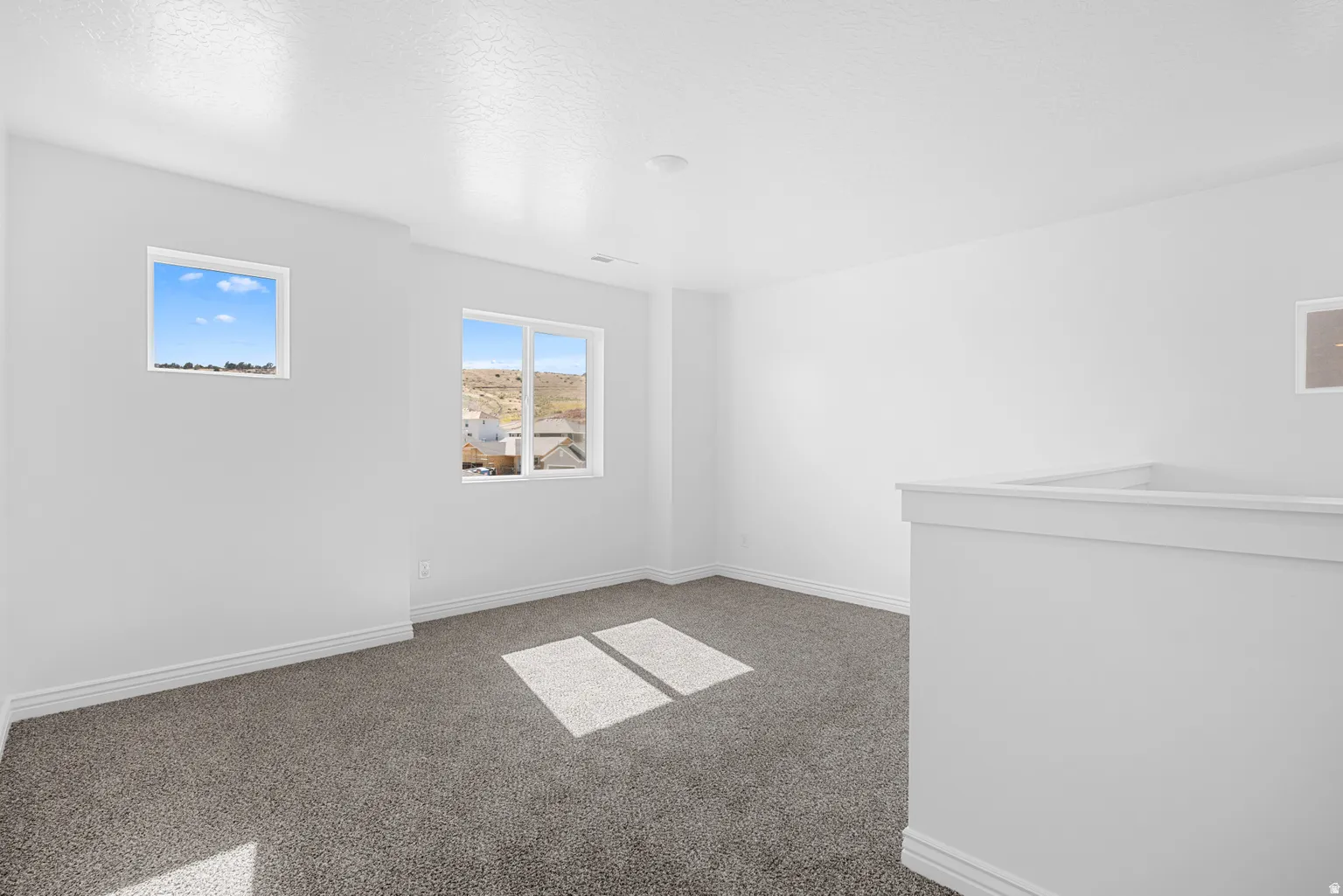 Carpeted room featuring multiple windows and a half-wall partition