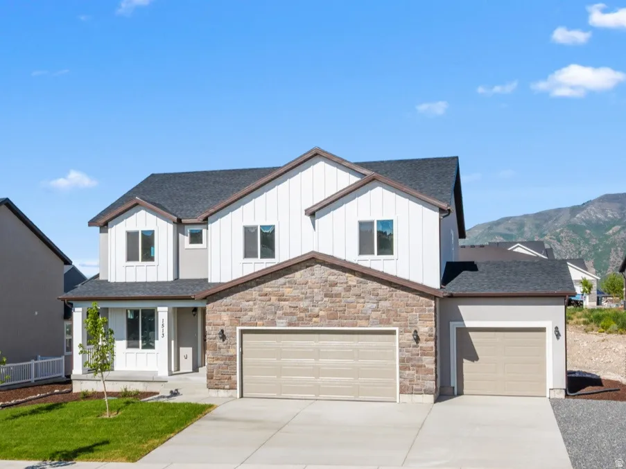 Contemporary exterior with stone accent, dual garage doors, and a mountain backdrop