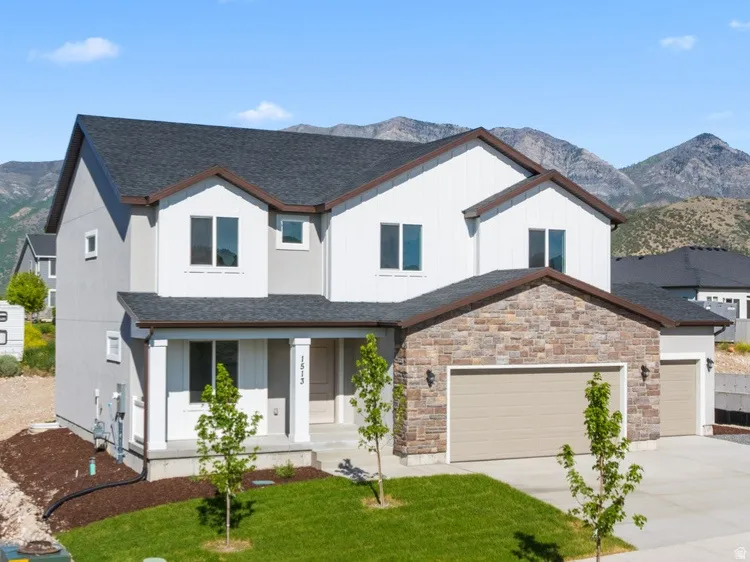 Contemporary two-story residence featuring a stone and stucco facade, a two-car garage, and a covered front porch