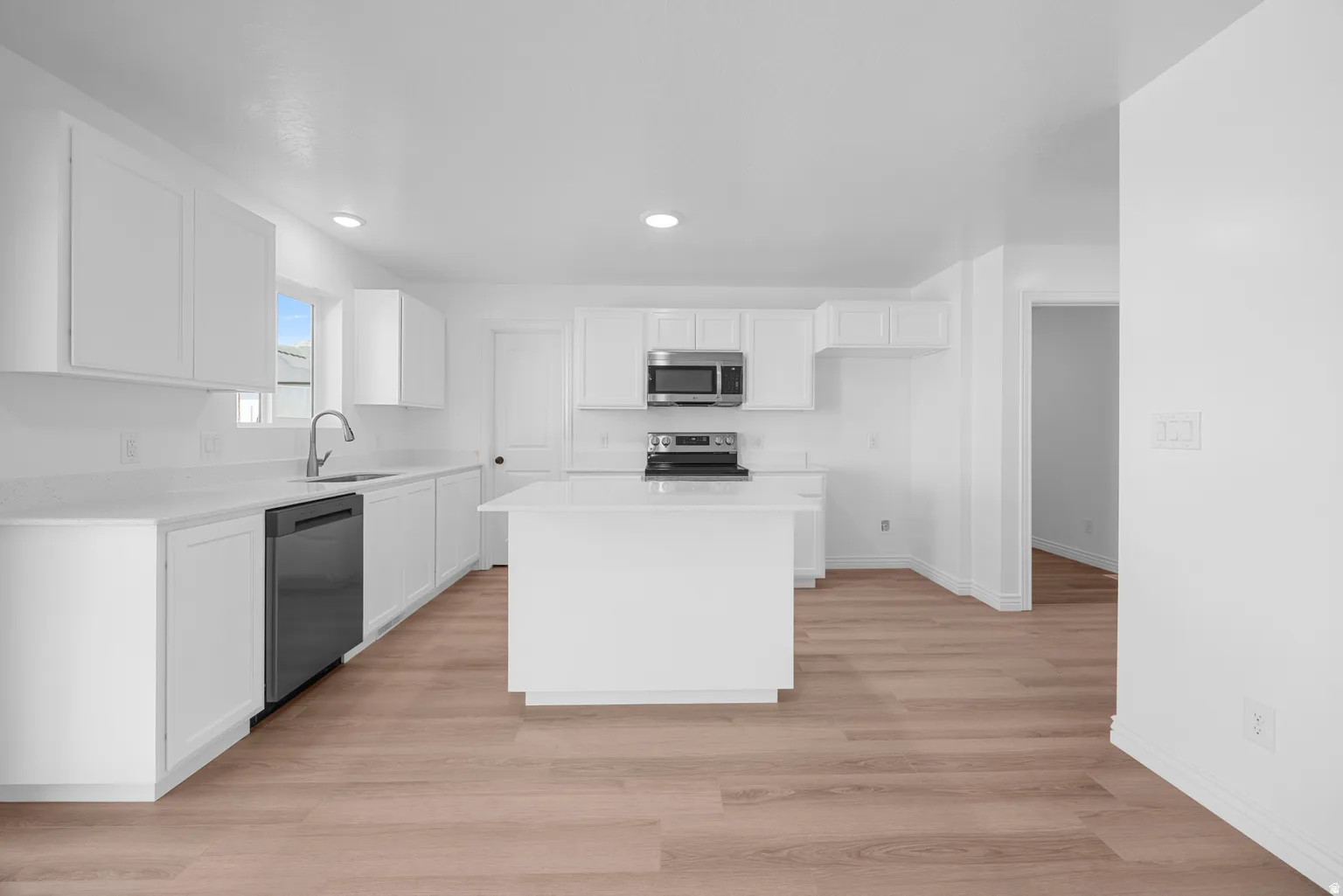 White cabinetry with brushed nickel hardware, stainless steel appliances, wood-finish flooring, central island, and recessed lighting