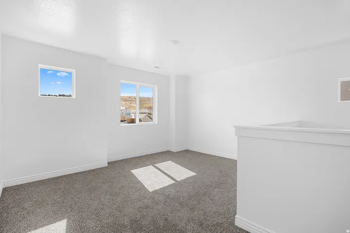 Carpeted room featuring multiple windows and a half-wall partition