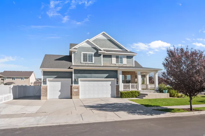 3 Car Garage. Crafted exterior featuring a covered porch, multiple garage bays, and a concrete driveway