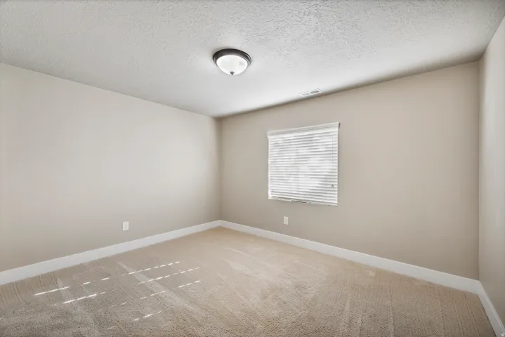 Bedroom 5. Neutral wall color, wall-to-wall carpeting, window with blinds, and flush mount lighting