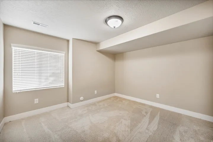 Bedroom 7. Neutral wall color, wall-to-wall carpeting, window with blinds, surface-mounted ceiling light fixture