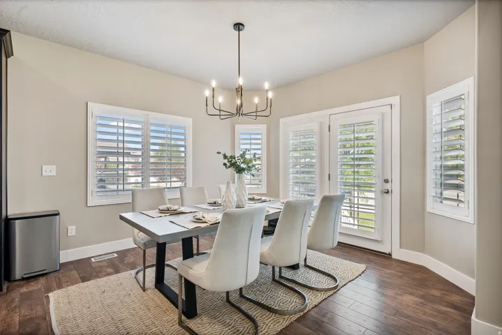 Recessed lighting, wood-finish flooring, white window shutters, and a modern chandelier
