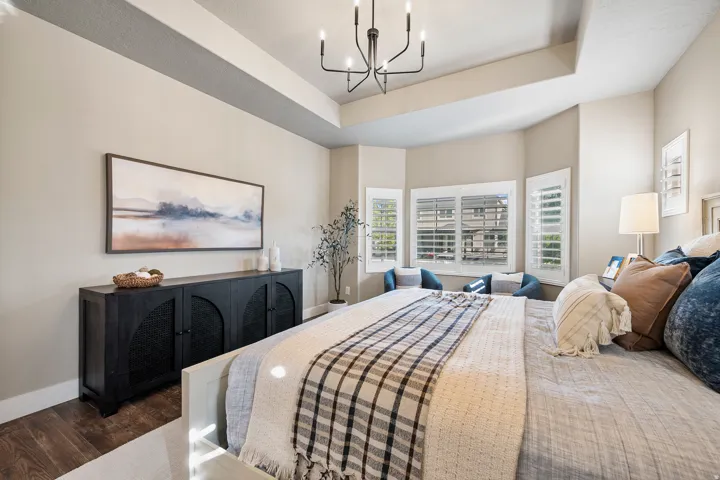 Tray ceiling, bay window, plantation shutters, wood-finish flooring, and a contemporary chandelier