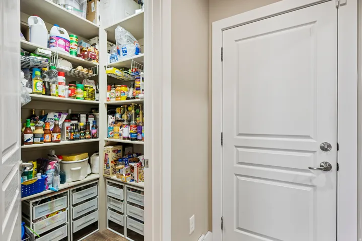 Walk-in pantry featuring built-in shelving, wire racks, and storage drawers