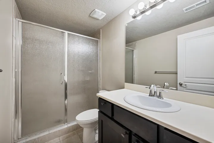 Bath 4. Shower with textured glass enclosure, dark wood-finish vanity, white countertop, and integrated oval sink