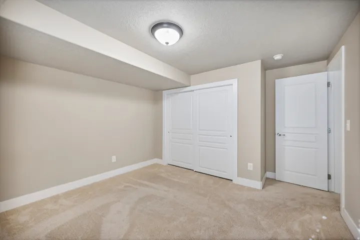 Bedroom 6. Neutral wall paint, plush carpet flooring, white trim, white panel doors, and white sliding closet doors