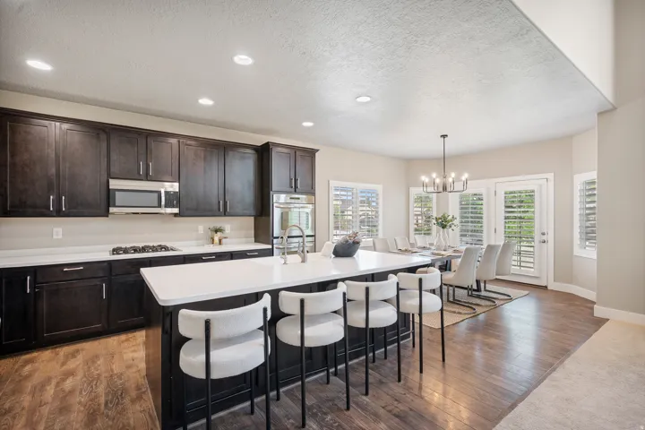 Kitchen featuring dark wood cabinetry, white countertops, stainless steel appliances, and a central island with seating