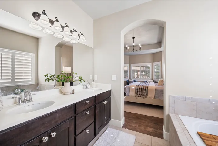 Double vanity with white countertop, dark wood-finish cabinetry, and chrome fixtures