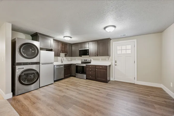 Kitchenette with dark wood-finish cabinetry, white countertops, and stainless steel appliances