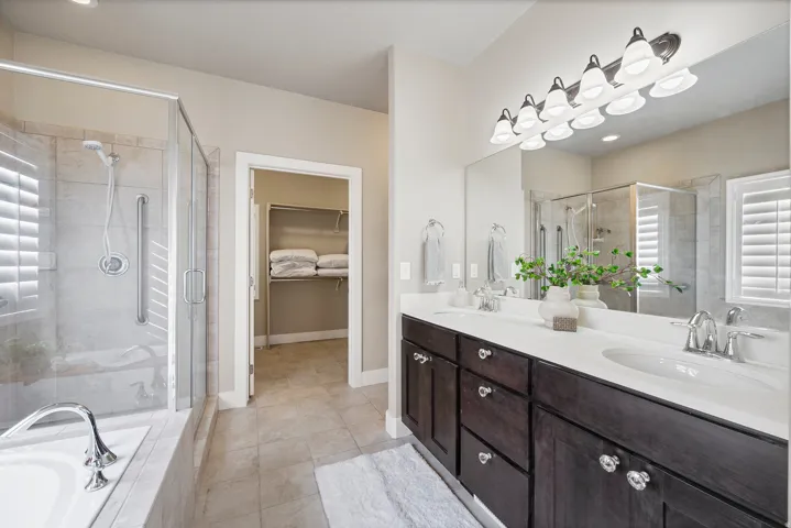 Dual vanity with dark wood-finish cabinetry, white countertops, and chrome fixtures