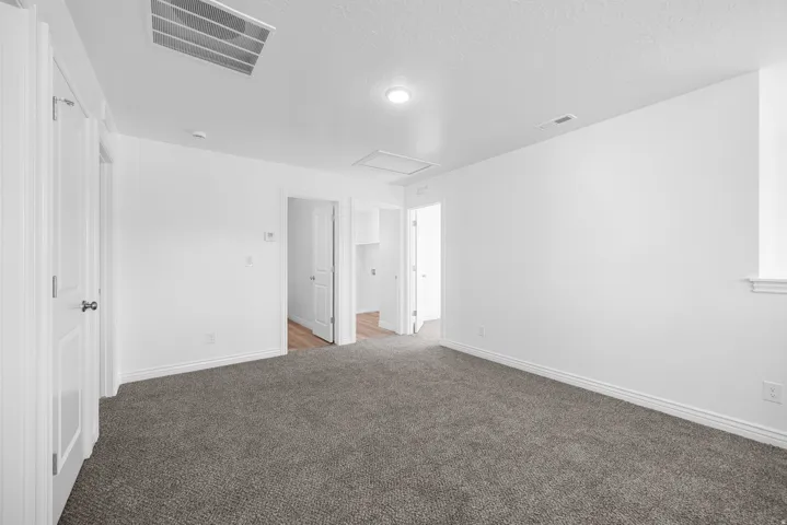 Carpeted flooring, white walls, multiple doorways, and recessed lighting