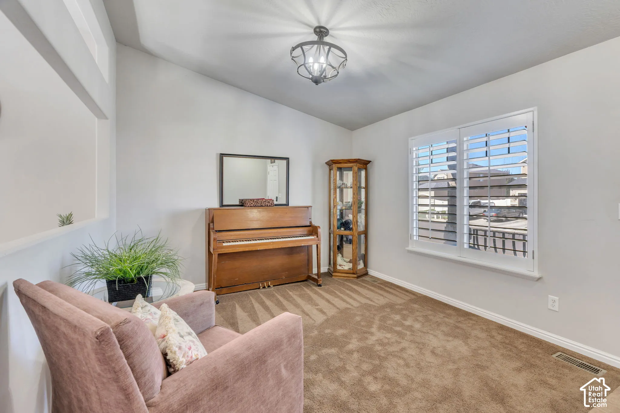Vaulted ceiling, white walls, and a window with white plantation shutters