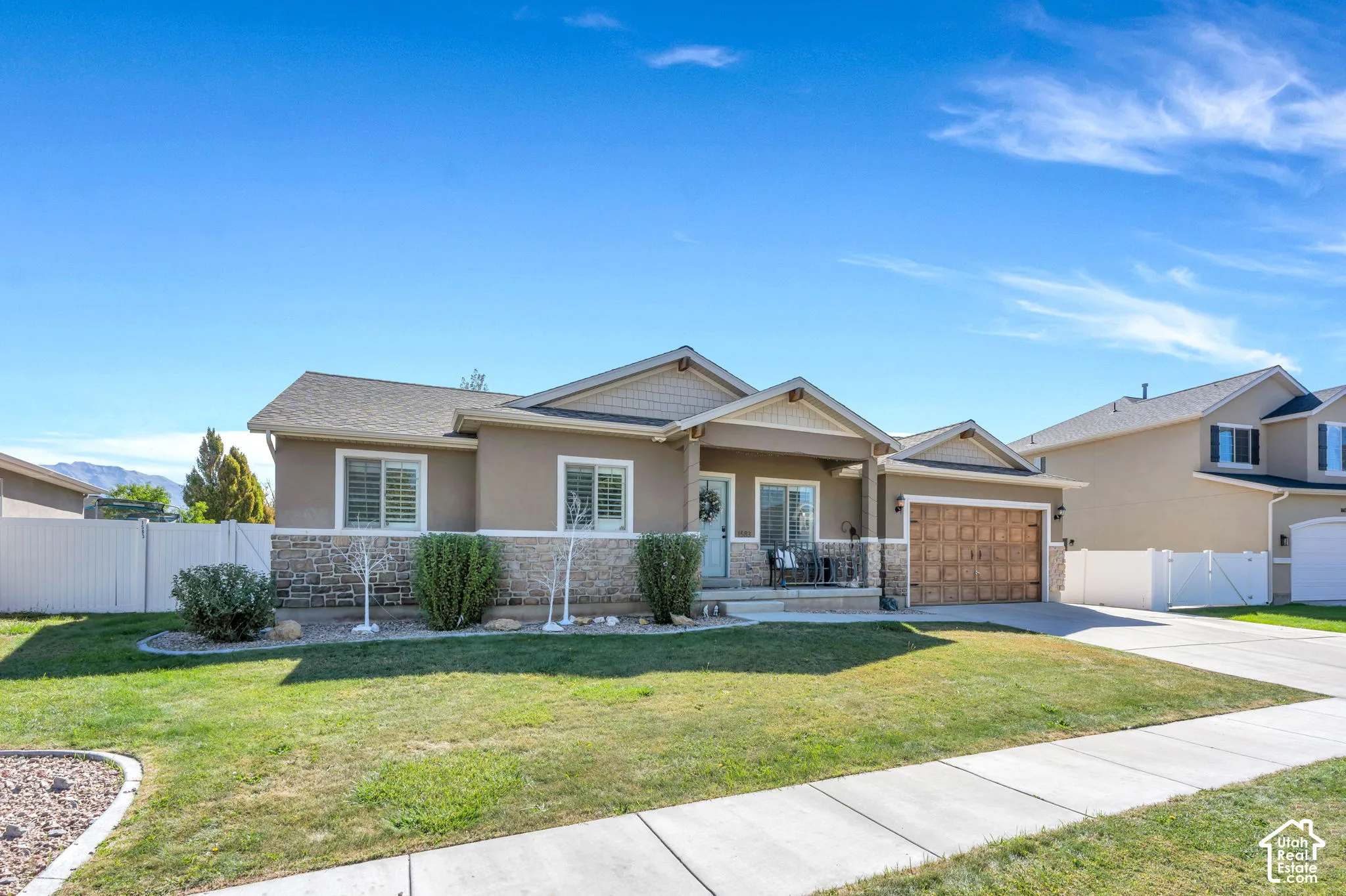Curb appeal featuring a stone veneer facade, covered porch, attached 3 car garage and a concrete driveway