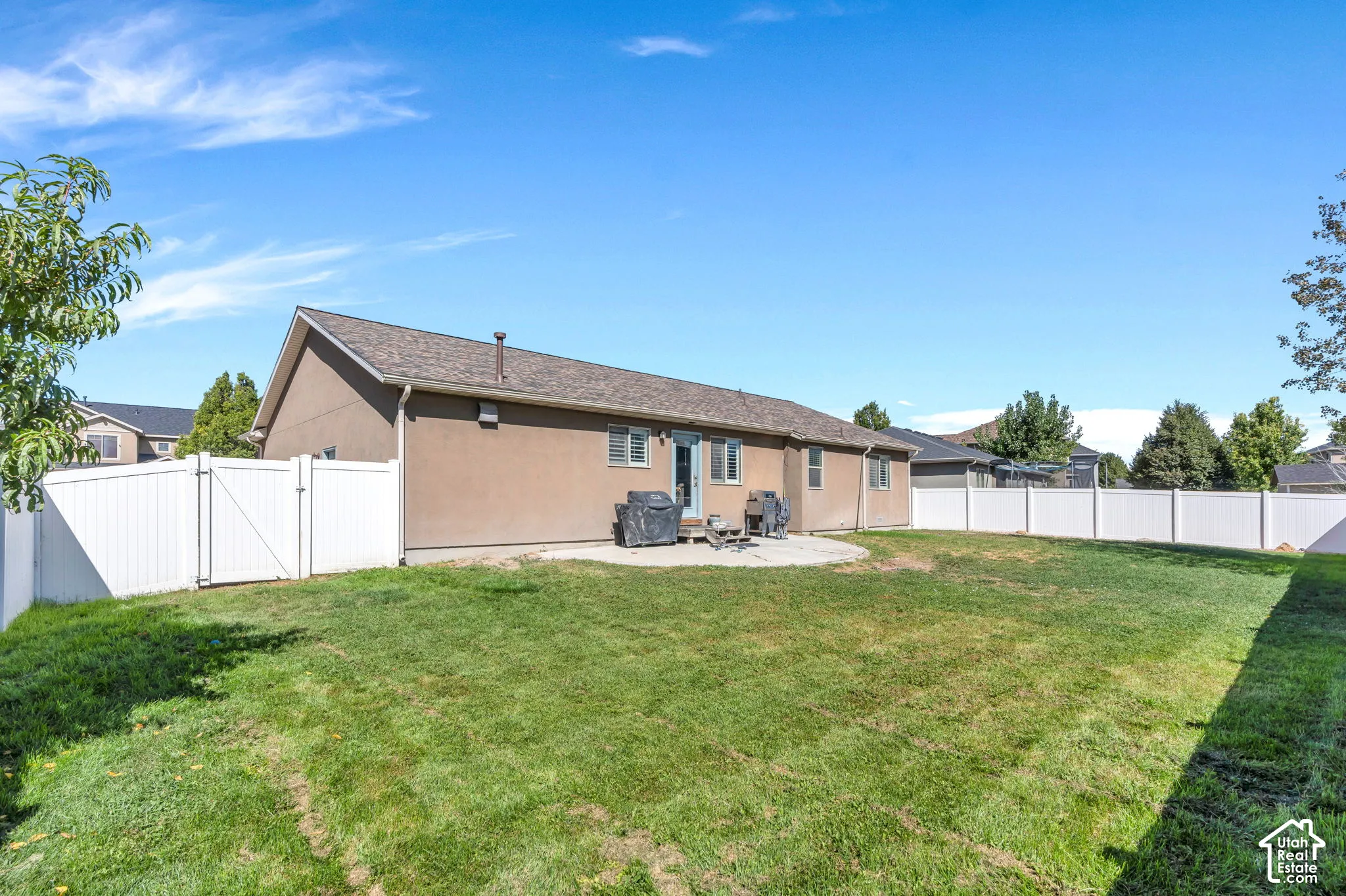 Expansive backyard with a manicured lawn, full vinyl fencing, and a concrete patio