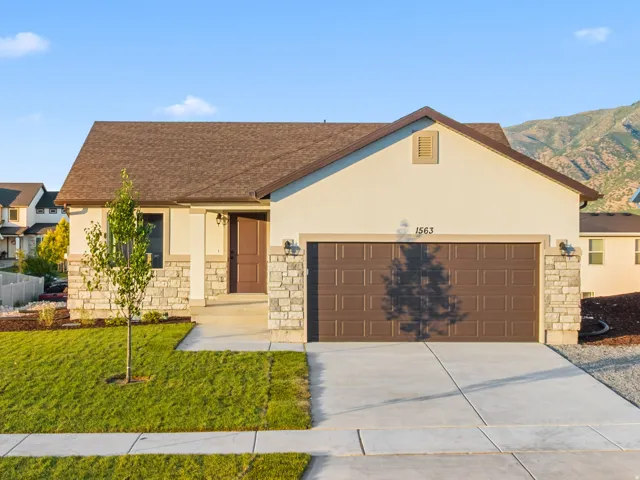 Single-story residence featuring a two-car garage, stone and stucco exterior, and a concrete driveway