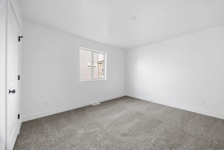 Neutral color palette with white walls, recessed ceiling lighting, gray carpet flooring, and a white window frame