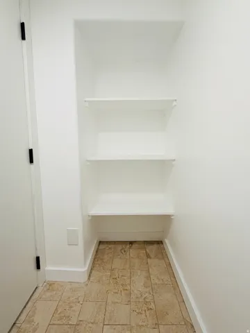 Built-in shelving unit with three white shelves and tiled flooring