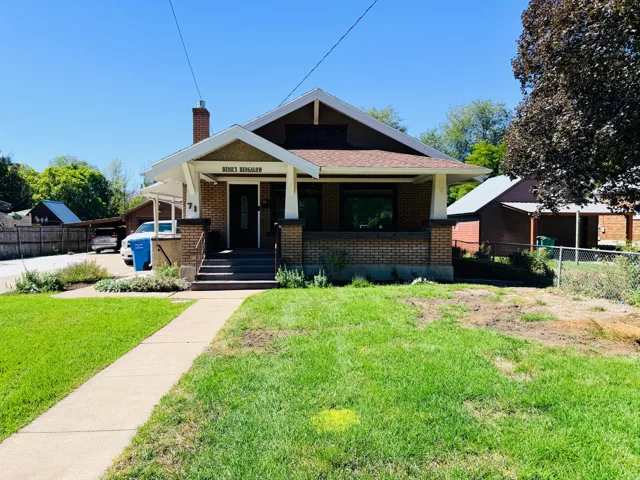 Bungalow-style residence featuring a brick facade, covered front porch, and peaked roofline