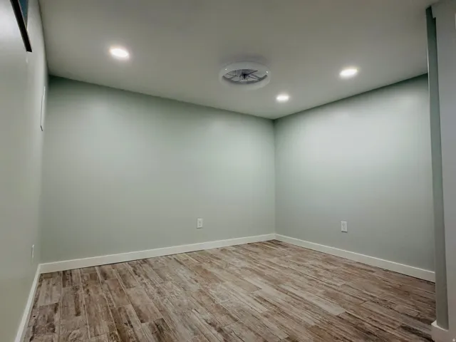 Wood-finish flooring with recessed lighting and a ceiling-mounted fan