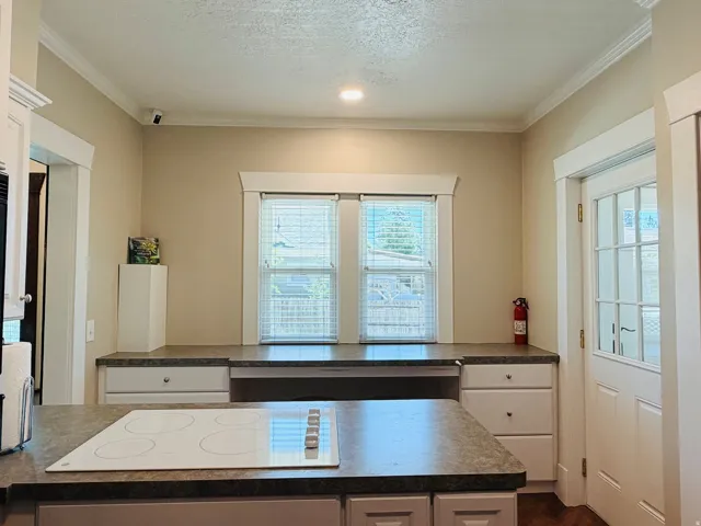 Built-in cooktop, extensive countertop space, white cabinetry, and crown molding