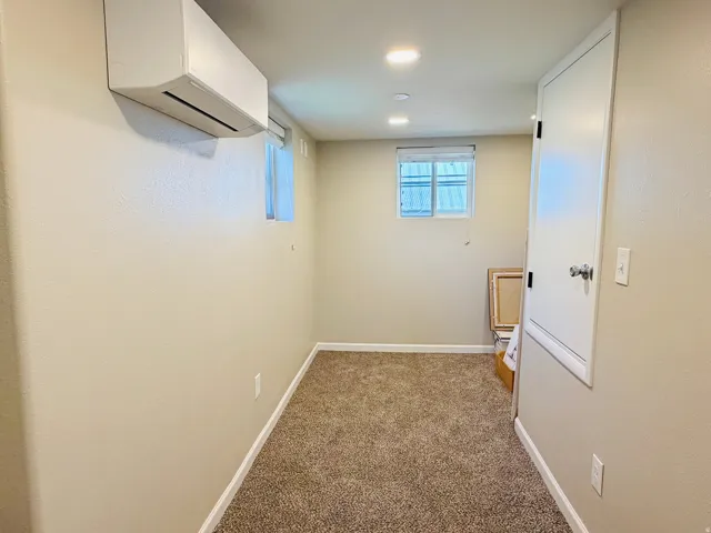 Mini-split climate control system, recessed ceiling lighting, textured wall finish, and a window for natural light