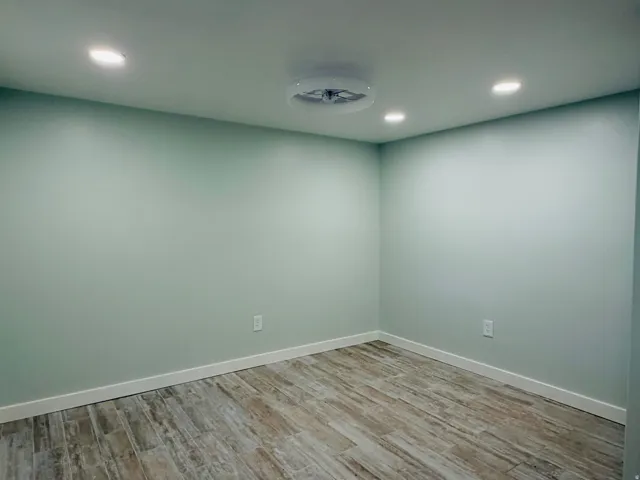 Recessed ceiling lights, wood-finish flooring, and light-toned wall paint