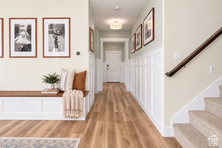 all to wall built in storage bench, welcoming entryway to the front door, and a wall with custom wainscoting detailing