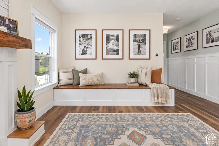 Cozy living room with wall to wall built in bench seating, abundant natural light, beautiful medium toned wood floors, fireplace, and custom accent wall