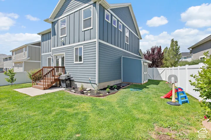 Expansive backyard featuring a manicured lawn, a white privacy fence, and a built-in shed