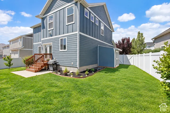 Spacious backyard featuring a wood deck, concrete patio, privacy fencing, a storage shed, and a landscaped garden bed