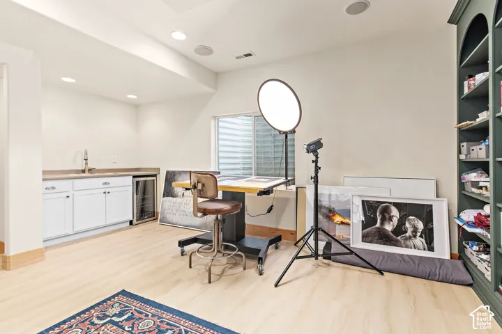 Basement wet bar with white cabinetry,  beverage refrigerator