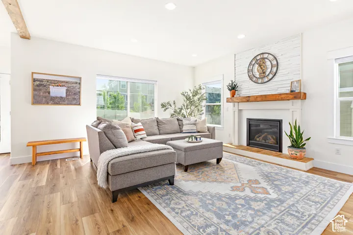 Cozy living room with abundant natural light, beautiful medium toned wood floors, fireplace, wall to wall built in storage bench seating, and custom accents
