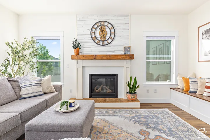 Cozy living room with  fireplace, abundant natural light, beautiful medium toned wood floors, wall to wall built in storage bench seating, and custom accents