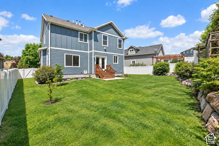 Expansive lawn with a white privacy fence and a rock retaining wall