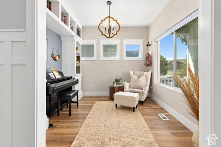 Cozy entry living room with custom built-in shelving, windows on two sides for plenty of natural light and a decorative chandelier