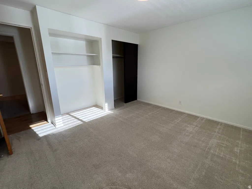Here's Bedroom 2 - without furnishings this time.  Built-in shelving, plush carpeting, bright white walls, and a recessed closet with dark bifold doors