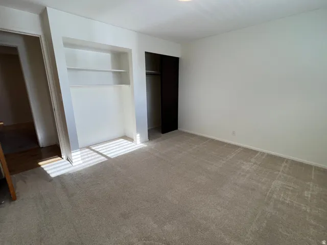 Here's Bedroom 2 - without furnishings this time.  Built-in shelving, plush carpeting, bright white walls, and a recessed closet with dark bifold doors