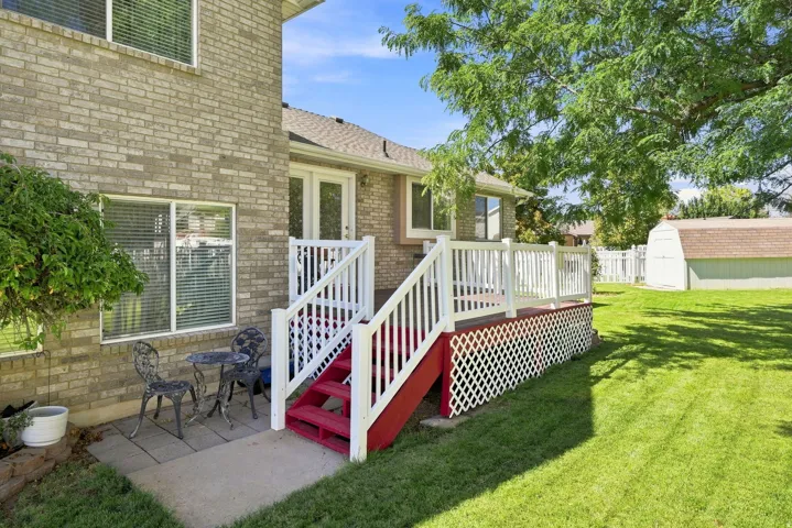 Brick exterior with white-framed windows, a red and white deck, and a green lawn
