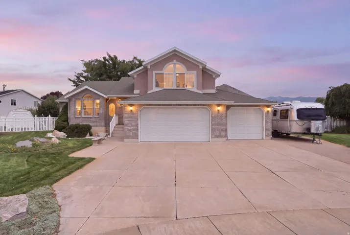 Two-story exterior with stucco and stone accents, concrete driveway, attached two-car garage, and arched window details
